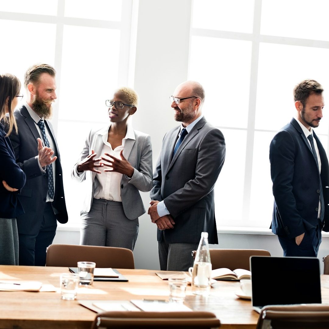 Groupe de professionnels discutant autour d'une table de conférence lumineuse.